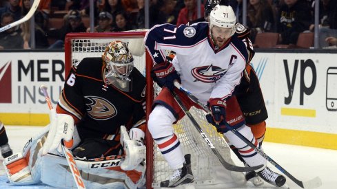 Nick Foligno keeps the puck away from the Ducks' John Gibson