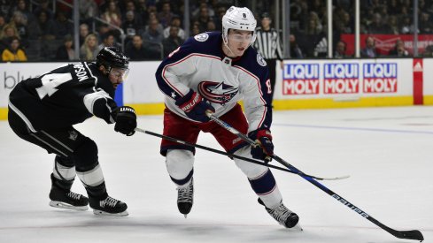 Columbus Blue Jackets defenseman Zach Werenski skates around Nate Thompson of the Los Angeles Kings.