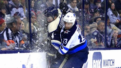 Columbus Blue Jackets defenseman Scott Harrington (4) is checked into the glass by Winnipeg Jets left wing Brandon Tanev (13) in the third period at Nationwide Arena. 