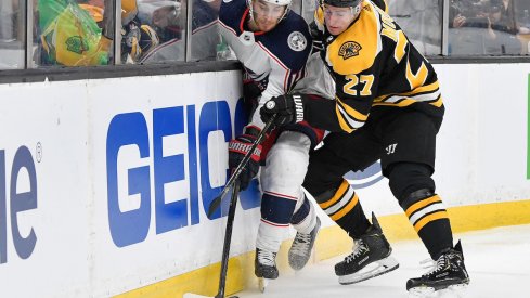 Columbus Blue Jackets center Alexander Wennberg fights for the puck against Boston Bruins defenseman John Moore.