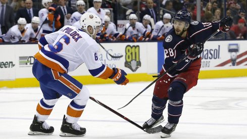 Oliver Bjorkstrand chips the puck past defenseman Ryan Pulock of the New York Islanders