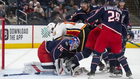 Nov 2, 2019; Columbus, OH, USA; Columbus Blue Jackets goaltender Joonas Korpisalo (70) covers the puck while Calgary Flames left wing Matthew Tkachuk (19) falls on him during the game at Nationwide Arena. Mandatory Credit: Jason Mowry-USA TODAY Sports