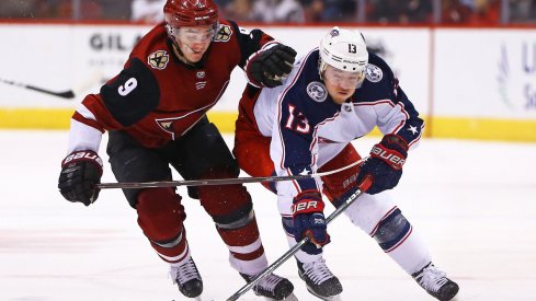 Jan 25, 2018; Glendale, AZ, USA; Arizona Coyotes center Clayton Keller (9) battles for the puck against Columbus Blue Jackets right wing Cam Atkinson (13) in the third period at Gila River Arena. Mandatory Credit: Mark J. Rebilas-USA TODAY Sports