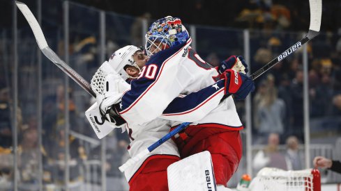 Columbus Blue Jackets goaltender Elvis Merzlikins (90) jumps into the arms of left wing Nick Foligno (71) after defeating the Boston Bruins in overtime at TD Garden.