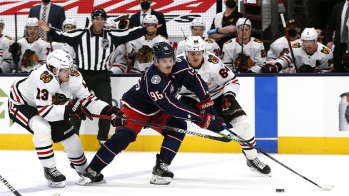 Columbus Blue Jackets center Jack Roslovic (96) splits the defense of Chicago Blackhawks center Mattias Janmark (13) and center David Kampf (64) during the third period at Nationwide Arena.