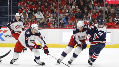 Dec 4, 2021; Washington, District of Columbia, USA; Columbus Blue Jackets left wing Eric Robinson (50) reaches for the puck in front of Washington Capitals center Connor McMichael (24) during the second period at Capital One Arena.