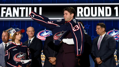 Columbus Blue jackets draft pick Adam Fantilli puts on his sweater after being selected with the third pick in round one of the 2023 NHL Draft at Bridgestone Arena.