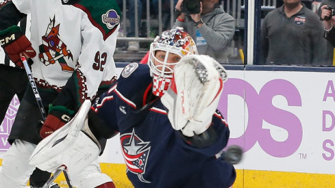 Columbus Blue Jackets goalie Elvis Merzlikins (90) makes a save with Arizona Coyotes center Logan Cooley (92) looking for a rebound during the first period at Nationwide Arena.