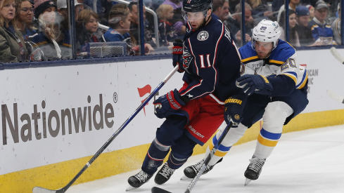 Adam Fantilli shields the puck from St. Louis Blues forward Brandon Saad