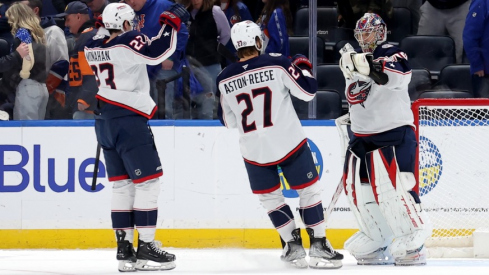 Columbus Blue Jackets goaltender Elvis Merzlikins (90) celebrates with centers Zachary Aston-Reese (27) and Sean Monahan (23) after defeating the New York Islanders in a shootout at UBS Arena.