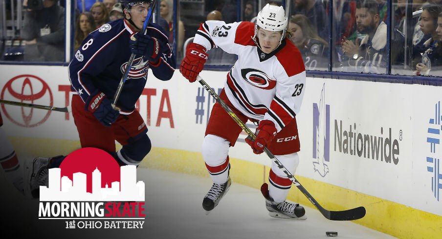 Hurricanes Brock McGinn tries to skate away from Zach Werenski of the Columbus Blue Jackets