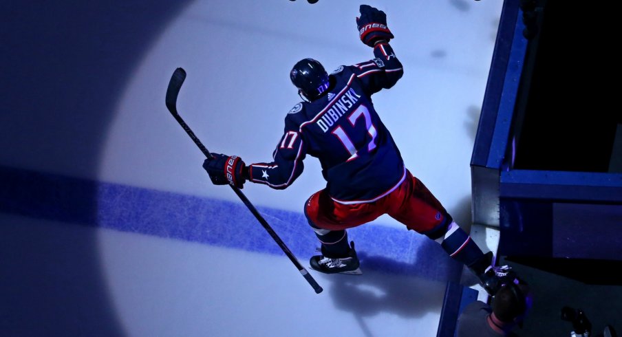 Brandon Dubinsky knocks pucks onto the ice during warm ups