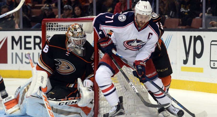 Nick Foligno keeps the puck away from the Ducks' John Gibson