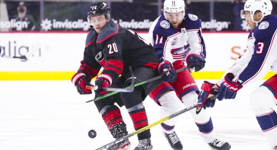 Carolina Hurricanes right wing Sebastian Aho (20) chips the puck away from Columbus Blue Jackets center Kevin Stenlund (11) during the third period at PNC Arena. 