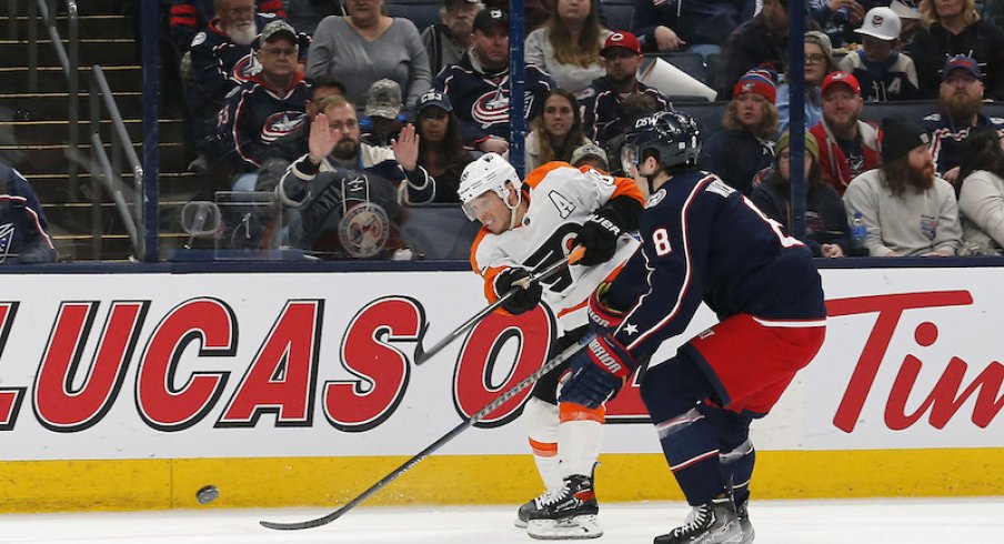 Philadelphia Flyers' Cam Atkinson shoots the puck over Columbus Blue Jackets' Zach Werenski at Nationwide Arena.