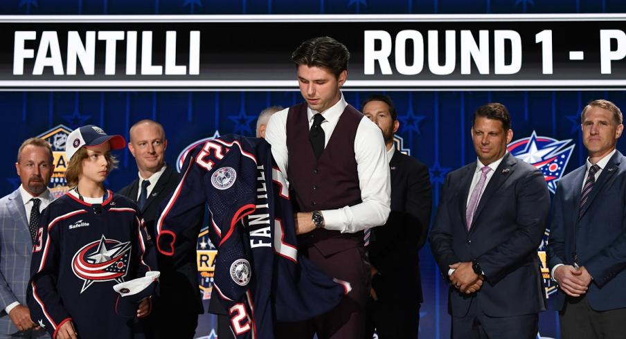 Adam Fantilli puts on a Blue Jackets jersey after being selected with the third pick in round one of the 2023 NHL Draft