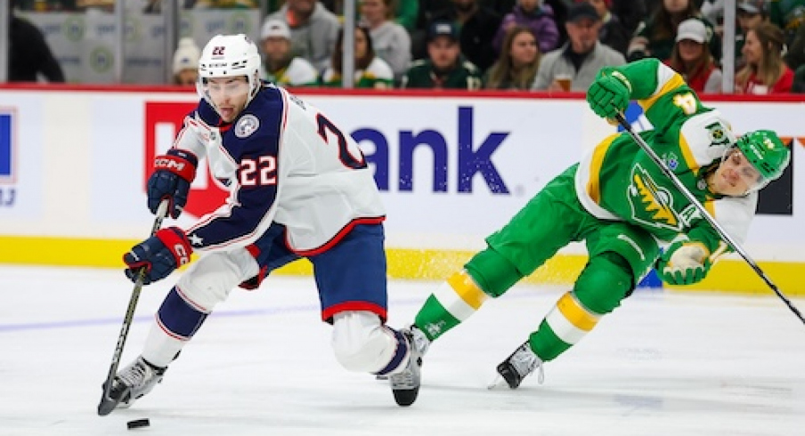 Columbus Blue Jackets defenseman Jake Bean (22) skates with the puck alongside Minnesota Wild center Joel Eriksson Ek (14) during the second period at Xcel Energy Center.