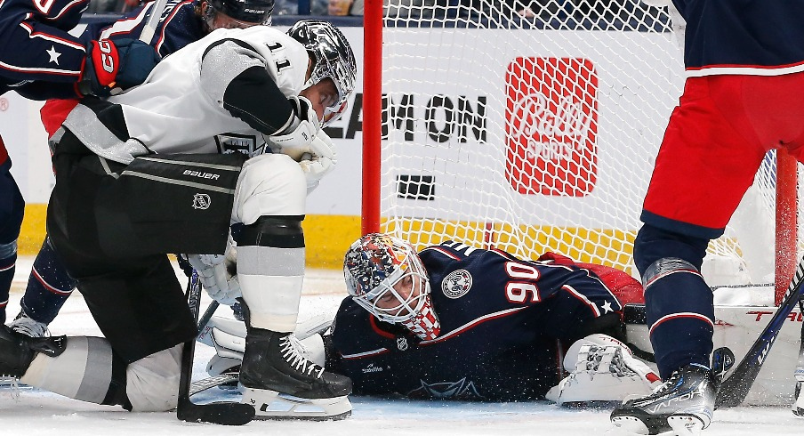 Columbus Blue Jackets goalie Elvis Merzlikins (90) covers a loose puck as Los Angeles Kings center Anze Kopitar (11) looks for the rebound during the second period at Nationwide Arena.