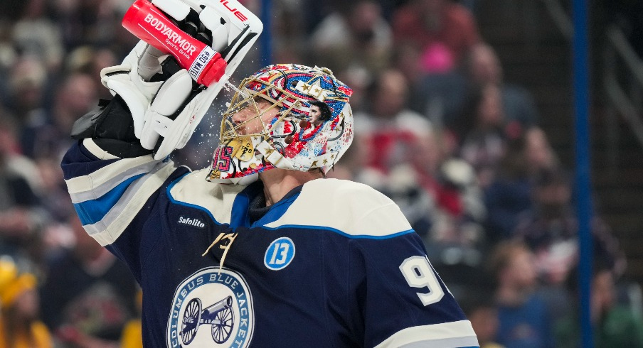 Columbus Blue Jackets goaltender Elvis Merzlikins (90) sprays his face with water during a stop in play against the New York Islanders in the first period at Nationwide Arena.